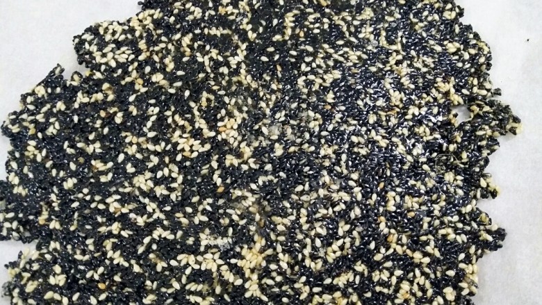 教你一招在家自制手工芝麻糖,把炒好的芝麻糖倒在面板上或倒在不粘烤盘上压实,一定要快呀,慢了就切不动了还易碎。