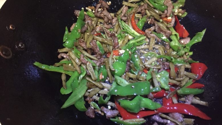 辣炒牛肉酸豆角,翻炒熟后放入青红辣椒，接着翻炒。因酸豆角已经比较咸，所以没有另外放调料，可根据个人口味放调料。