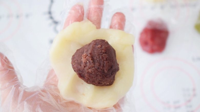 冰皮月饼,取一份原味的面团,按压成圆形,放入豆沙馅