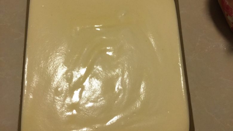 肉松小贝,将蛋糕糊倒入不粘烤盘中,将烤盘举起距离案面10cm处震泡2次