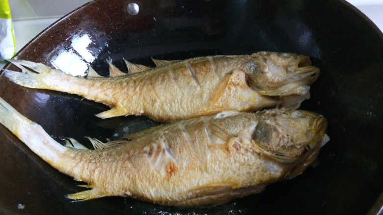 新文美食 红烧黄花鱼,全部炸好,留适量油,在把两条黄花鱼放入锅中。