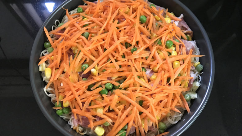 鸡蛋面披萨,然后把准备好的配料,青豆,玉米粒,胡萝卜和培根分别放在上面。