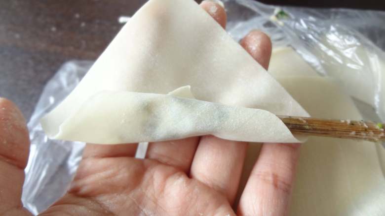 时蔬鲜肉小馄饨,用筷子取一点馄饨馅放在<a style='color:red;display:inline-block;' href='/shicai/ 4453'>馄饨皮</a>上，将<a style='color:red;display:inline-block;' href='/shicai/ 4453'>馄饨皮</a>卷起，抽出筷子两端向中间捏合