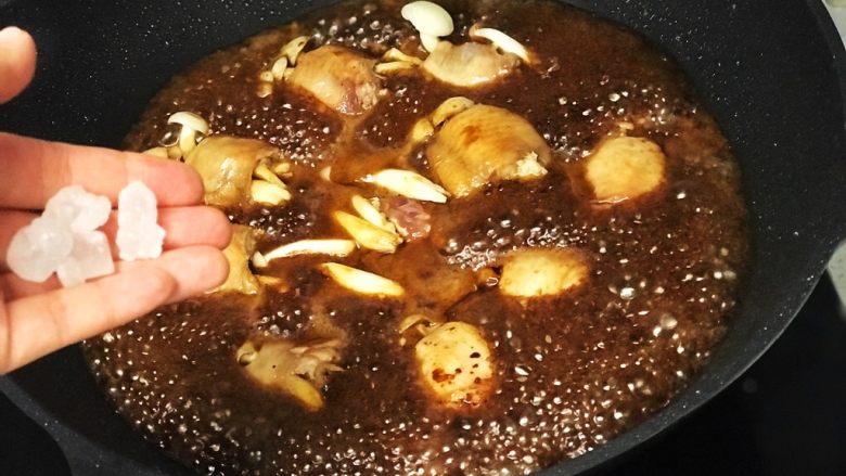 红烧鸡翅白玉菇,倒入热水没过鸡翅,放入4粒冰糖;