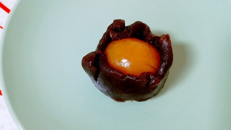 蛋黄酥,油酥皮松弛的时间里把蛋黄酥的馅做好,搓圆的豆沙馅用手压扁,包住咸蛋黄搓圆,盖上保鲜膜备用。