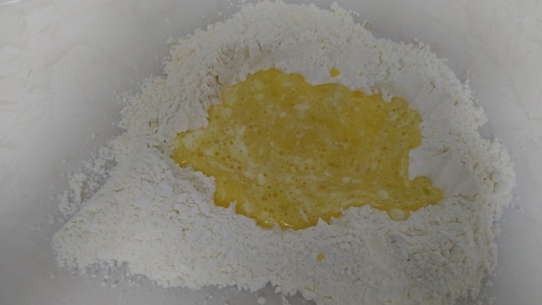 开口笑,面粉倒入操作台上,中间挖坑,倒入搅拌均匀的蛋液。