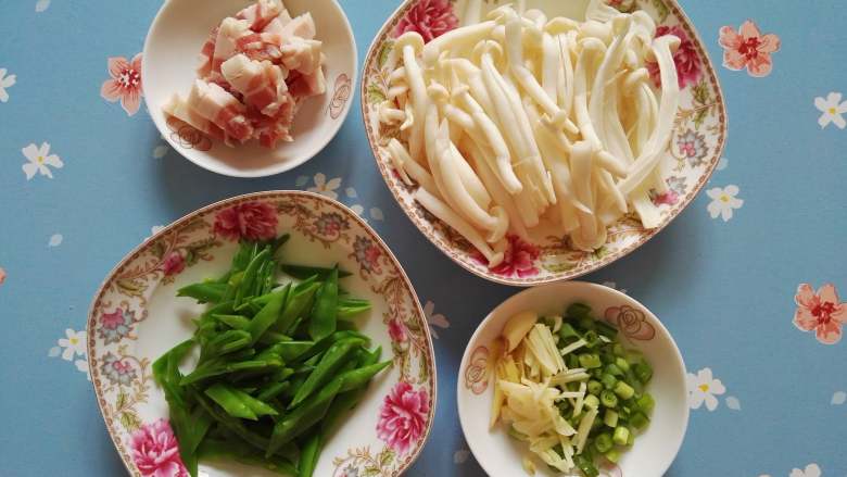 香而不腻、好吃又下饭的白玉菇荷兰豆炒五花肉,五花肉切条,白玉菇洗净将大一些的撕成两半,荷兰豆洗净焯水切条状,姜切丝,蒜切丝,葱切葱花。