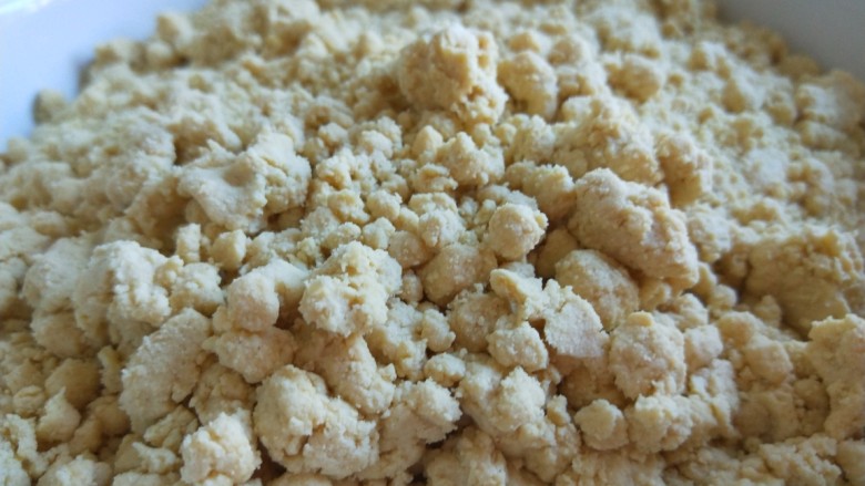 玫瑰豆沙黄面炸糕,用温水适量倒入,一边倒入水 一边搅拌均匀,不能有干面,也不能太软,如图所示,均匀的小面疙瘩就可以了。