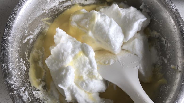 巧克力甘纳许淋面蛋糕(6寸),把三分之一的蛋白霜倒入蛋黄糊中翻拌均匀。