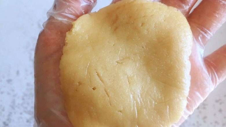 传统双酥果仁月饼(木糖醇糖浆),取一个油皮部分的面团在手中按扁,面团特别软,在掌心轻按即可