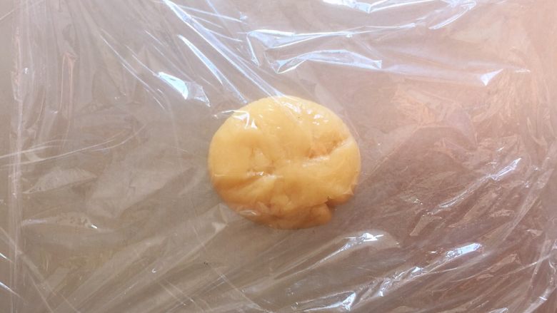 传统双酥果仁月饼(木糖醇糖浆),取一个包好的面团放在操作台上,面团上下层各铺一层保鲜膜,这样方便操作