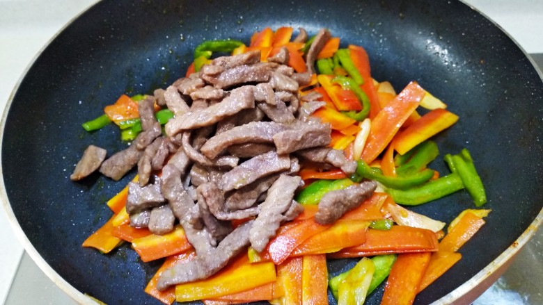 青椒胡萝卜炒牛排,倒入牛肉条