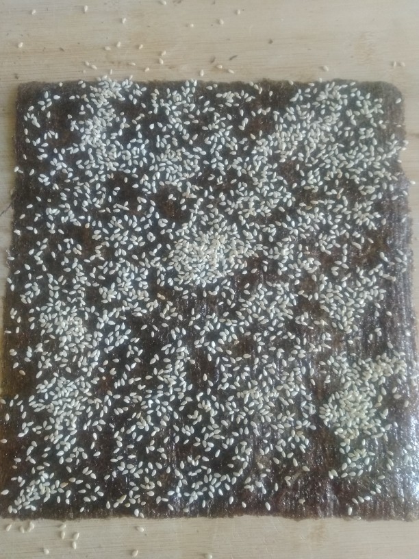 海苔夹心脆,把熬好的酱汁用细毛刷,薄薄的刷一层到<a style='color:red;display:inline-block;' href='/shicai/ 279'>海苔</a>粗糙的一面上。一定要刷均匀,并且要薄。然后撒上<a style='color:red;display:inline-block;' href='/shicai/ 678'>白芝麻</a>,把另一片<a style='color:red;display:inline-block;' href='/shicai/ 279'>海苔</a>同样薄薄的刷上一层酱汁。两片重叠在一起,用擀面杖擀平。在这里要注意啦!一定要正反都要擀一遍