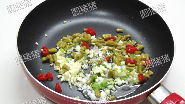 铁板水晶粉,炒锅热油,放入葱,姜,蒜末,红椒圈,酸豆角炒出香味。