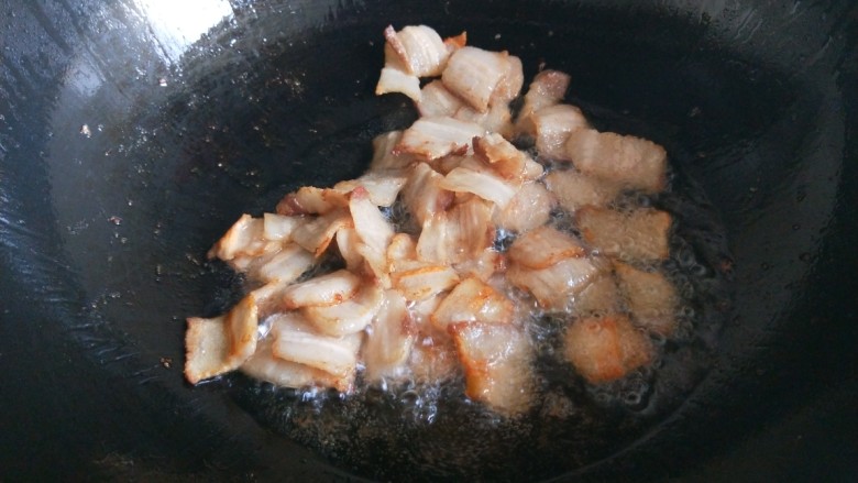 新文美食 五花肉炒蛇豆,锅中倒入适量油烧热,放入五花肉煸炒出油。