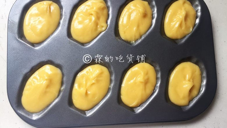 玛德琳(原味),冰箱里取出面糊,在室温下放置片刻,等到面糊重新恢复到可流动状态时,可直接用勺或者装入裱花袋再挤入模具中,九成满。