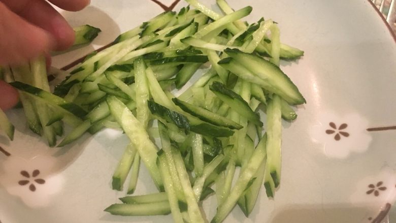 麻辣鸡丝,接着先将小黄瓜丝铺进盘里