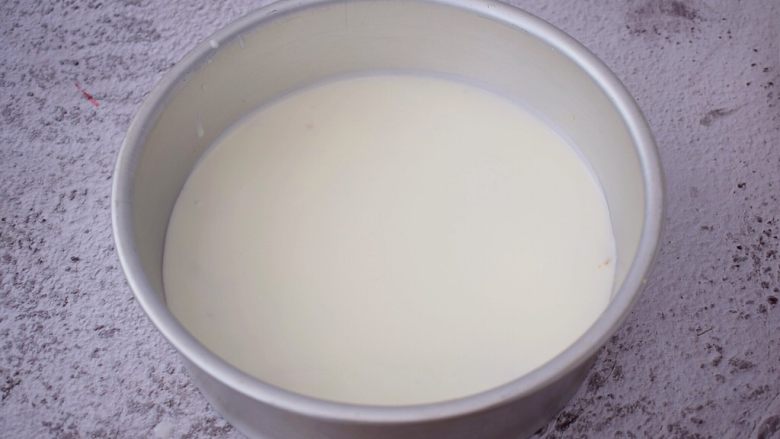彩虹慕斯蛋糕(八寸),把模具从冰箱取出来,先把白色慕斯糊倒入并轻轻拿起模具慢慢摇一摇,使慕斯均匀的分布于整个底部