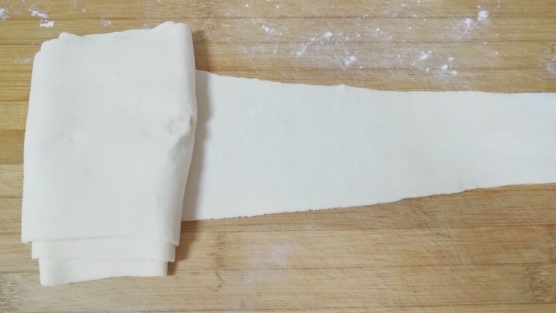 千层饼,用擀面杖擀成一头宽一头窄的面片(家里案板小,可以撒上干面粉把擀好的一边叠起来)。