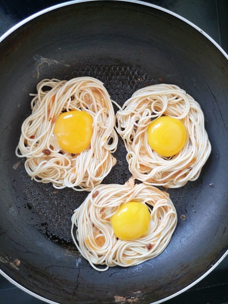 鸟巢蛋面饼,面饼凝固好后,再将蛋黄打入,如图所示,盖上锅盖焖一会就好了。