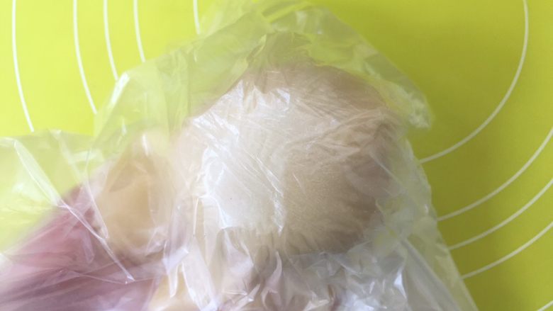 双蛋黄莲蓉月饼,揭掉一层保鲜袋,放上莲蓉蛋黄馅,之后倒扣在手上,揭掉保鲜袋,收好收口;