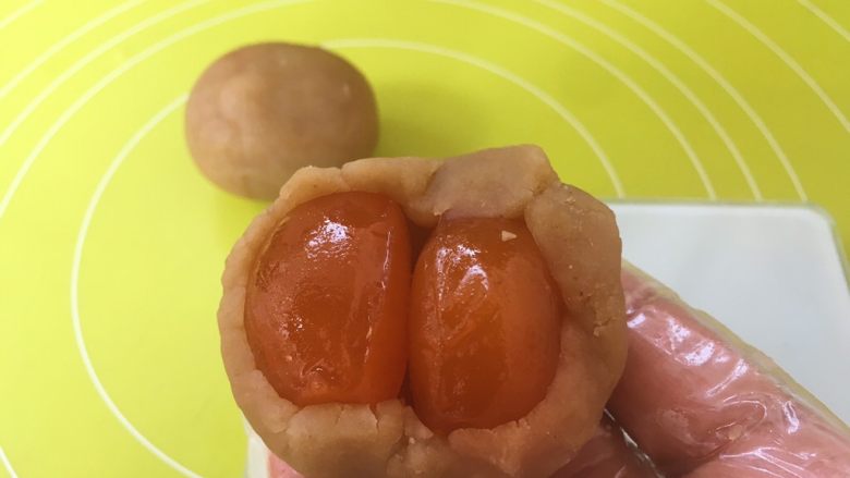 双蛋黄莲蓉月饼,包裹上两颗咸蛋黄,用双手虎口部分,一点点推揉莲蓉馅,将咸蛋黄包裹好;