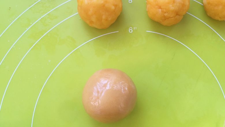 爱心金沙月饼,包裹好的月饼面团用手掌搓圆,搓圆的时候可以观察面团的表层是否有气泡,气泡可以用牙签扎破,之后再搓圆,表面光滑即可;