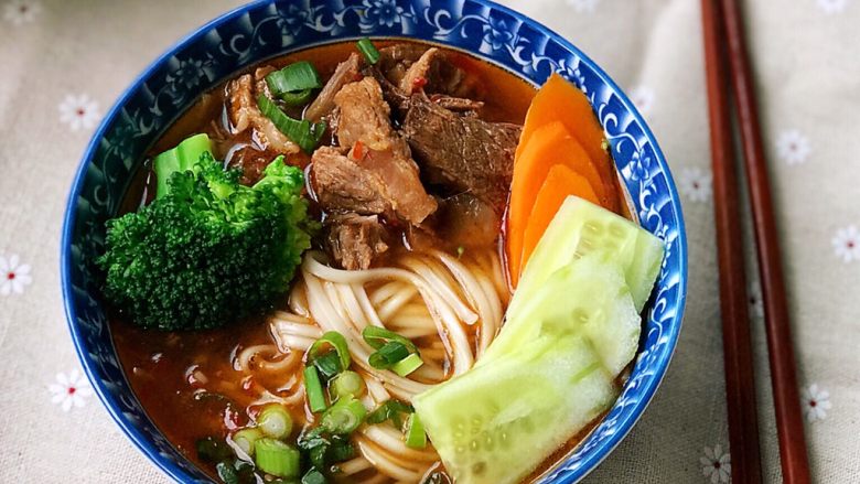 铸铁珐琅锅·红烧牛肉面,面煮好后,舀两勺面汤,然后捞面盛碗里,再舀两三勺牛肉和汤汁,浇在面上,摆上西蓝花、胡萝卜和黄瓜片,撒上一把葱花,齐活儿!喷香的红烧牛肉面,开动!