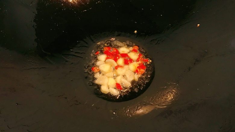 小炒牛肉,锅中少许油，放入蒜片和小辣椒圈，炒香。