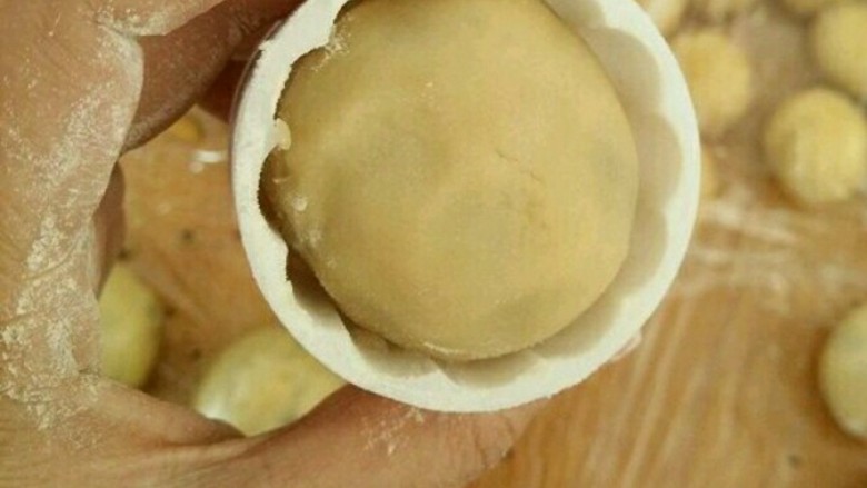 芝麻馅月饼,放点熟粉到月饼模具里,转一圈再倒出来。把月饼坯放进去,用力往下压出月饼。同时烤箱上下管预热190度。