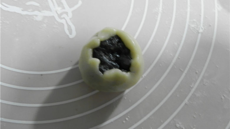 广式黑芝麻月饼,饼皮包住一个芝麻馅30克,用虎口慢慢把饼皮往上推(尽量做到让月饼皮均匀覆盖在馅外面。不均匀的地方可适当推补一下,保证完美),收好口。