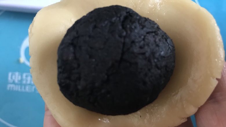 低油低糖黑芝麻豆沙~广式月饼,然后取一个饼皮压扁放入揉好的馅料,再揉成圆形。