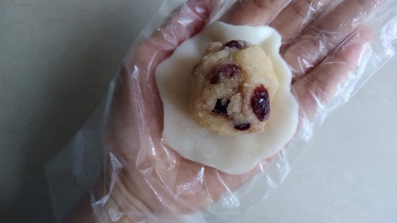 椰蓉蔓越莓冰皮月饼,饼皮分成每个25克,在手掌上压扁放入馅料。