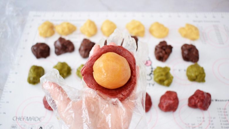 彩色月饼,取一份饼皮,放在掌心按压成圆饼形,再放入内馅