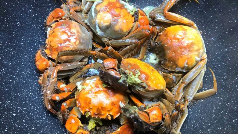 油焖大闸蟹,煎至蟹壳发红,翻面继续煎制