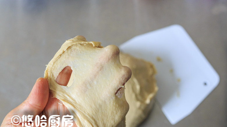 咖啡核桃吐司,厨师机继续搅拌,慢速3分钟、中速4分钟,取出面团在台面上摔打几下,至面团能拉出薄膜即可。