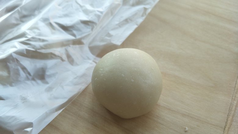 香酥红豆饼(老婆饼),用虎口位置,把油酥包入油皮,捏紧。放置到面板上,全部包好,覆盖保鲜膜放置一会。