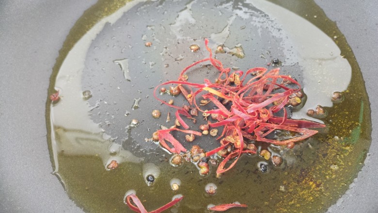 下酒菜牛肉炒酒鬼花生,接着另起锅,把辣椒丝和花椒放进去炒香。