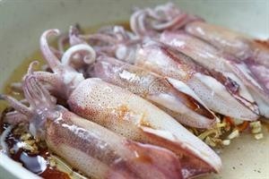 油焖海管,下辣椒,然后把小管铺在姜蒜上,到一些酱油、料酒,盖上锅盖,中火焖2分钟