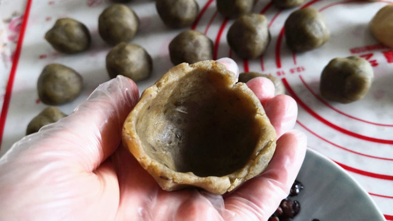 绿豆沙蜜豆月饼,取一个绿豆沙球用大指按一下,呈现如图形状,
