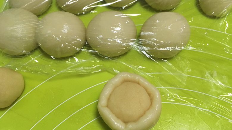 酥皮伍仁月饼,包裹上油酥皮材料,放在手的虎口位置,一点点推揉面团,将油酥皮包裹上,捏紧收口,做好后继续盖保鲜膜