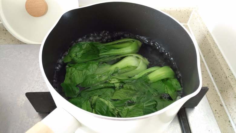 鱼肠鲜虾海鲜面,锅中水烧开,加少许盐、几滴食用油,下青菜焯烫1分钟捞出备用