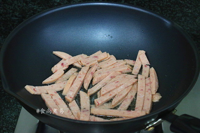 午餐肉包菜炒米粉,热锅,倒入食用油,将午餐肉煸炒一会儿