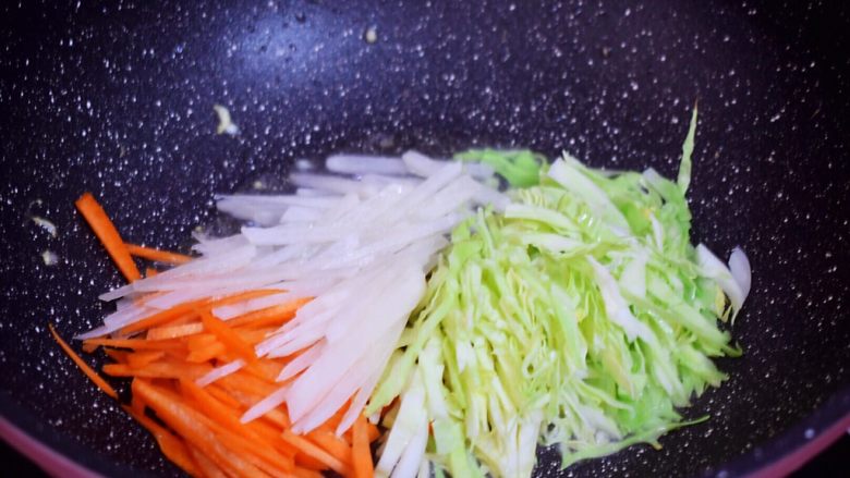 炒河粉,原锅倒入适量的食用油烧热,再放入胡萝卜、白萝卜、包菜翻炒至变软