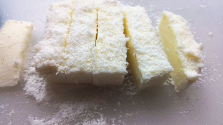 牛奶椰丝小方,切板上铺一层椰蓉,取出来,切成适当的小块,