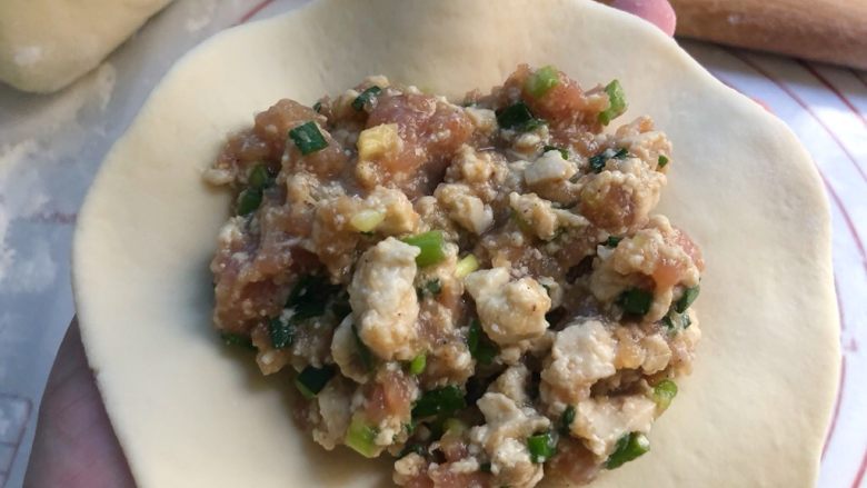 豆腐包子,把面片放入左手上,舀2勺馅料放到面团上包好