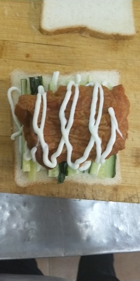 鸡腿三明治,最后放上烤好得奥尔良鸡腿肉在挤上最后一层沙拉酱 盖上最后一层吐司切片