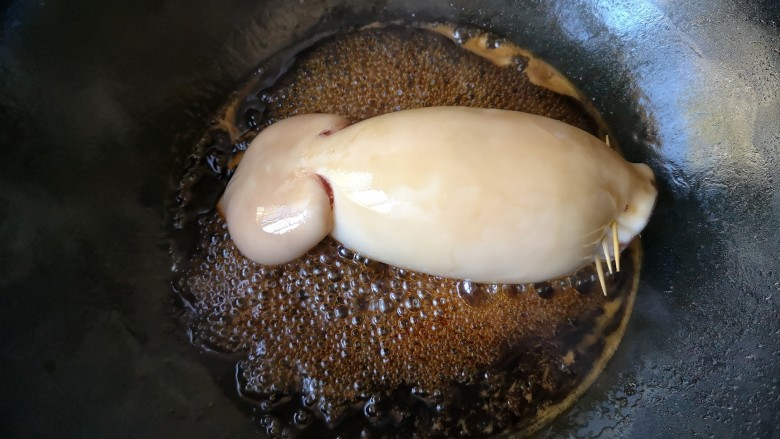 照烧鱿鱼包饭,转小火放入塞好米饭的鱿鱼,让鱿鱼均匀沾满照烧汁。