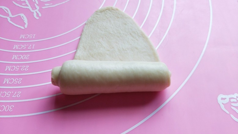 香葱芝士面包~烘焙小白必做,取一块小面团,用擀面杖擀长舌状。由上到下卷起来。