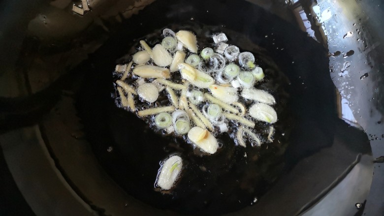 手撕包菜——这个菜狠费饭,锅中适量油烧至7成热,下入葱花,蒜片,姜丝饱出香味。